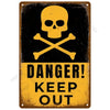 A vintage metal wall art sign featuring a yellow skull and crossbones symbol on a black background with the text DANGER KEEP 