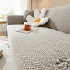 A light gray thick jacquard sofa cover featuring a white, petal-shaped accent cushion and an orange mug on the surface.