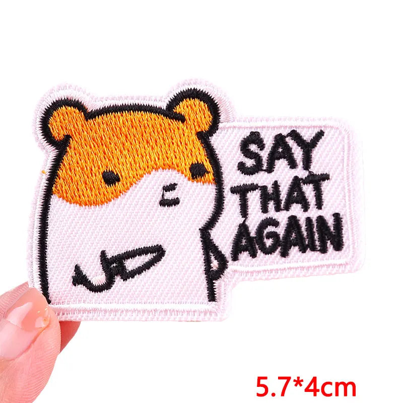 A pink embroidered patch featuring a cartoon tiger face with black outlines and orange fur, with the text SAY THAT AGAIN.