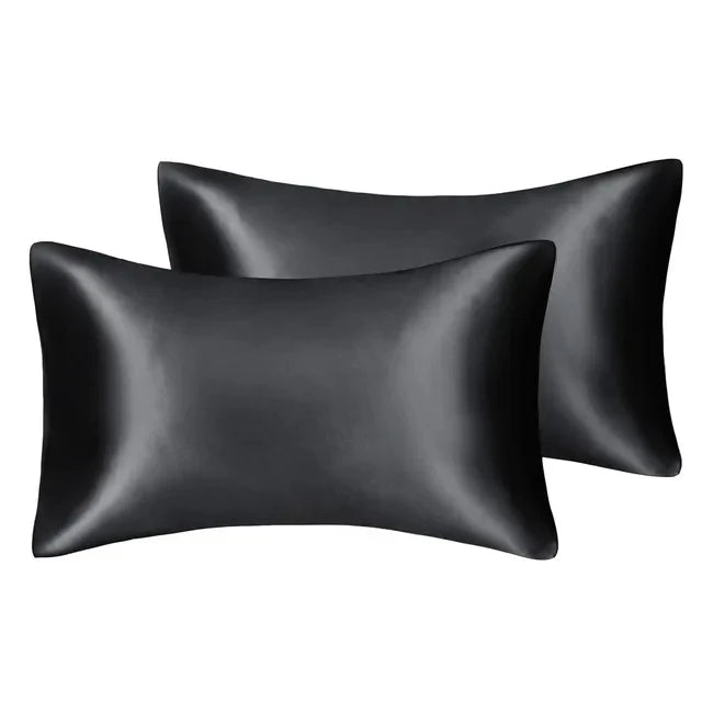 A set of three black silky satin pillow covers, including a standard and a larger queen size pillow.