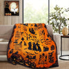 An orange flannel blanket featuring black silhouette designs of witches and spooky elements.