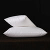 A stack of white natural goose down and feather sleeping pillows resting on a dark surface.