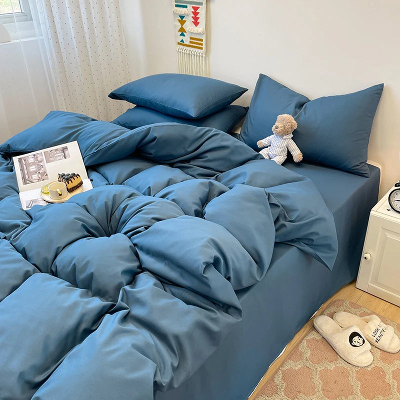 A blue solid color 3-piece duvet cover set with matching pillowcases is displayed on a bed.
