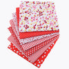 A stack of red, white, and pink floral dot pattern cotton fabric squares for DIY crafting.
