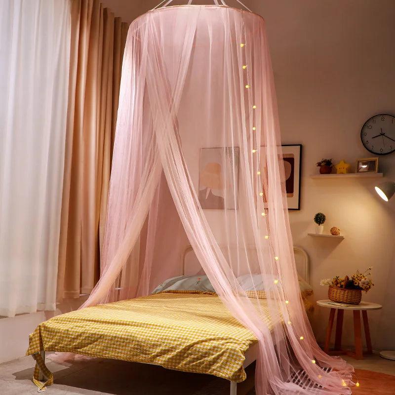 Pink sheer mosquito net canopy draped over a bed in a bedroom setting.