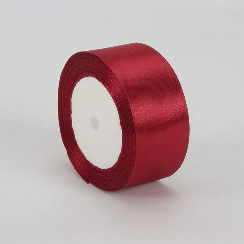 A roll of deep red satin ribbon, 4cm wide, used for crafts and gift wrapping.