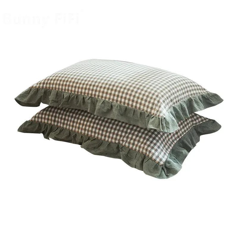 A set of two washed cotton pillowcases in a soft plaid pattern with ruffled edges.