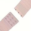 A close-up view of a light pink bra strap extender with decorative stitching and multiple hooks.