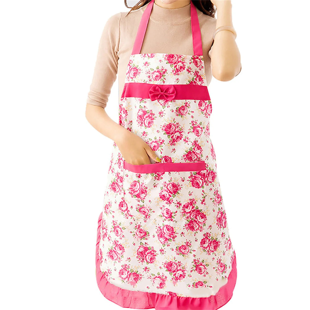 A pink floral print kitchen apron with pockets and an adjustable pink belt worn by a person.