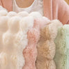 A close-up of various pastel and neutral colored plush rabbit fur sofa cushion covers.