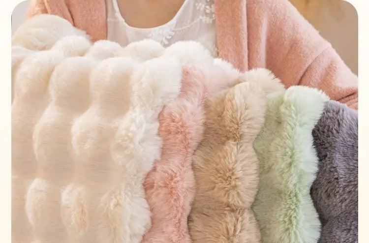 A close-up of various pastel and neutral colored plush rabbit fur sofa cushion covers.