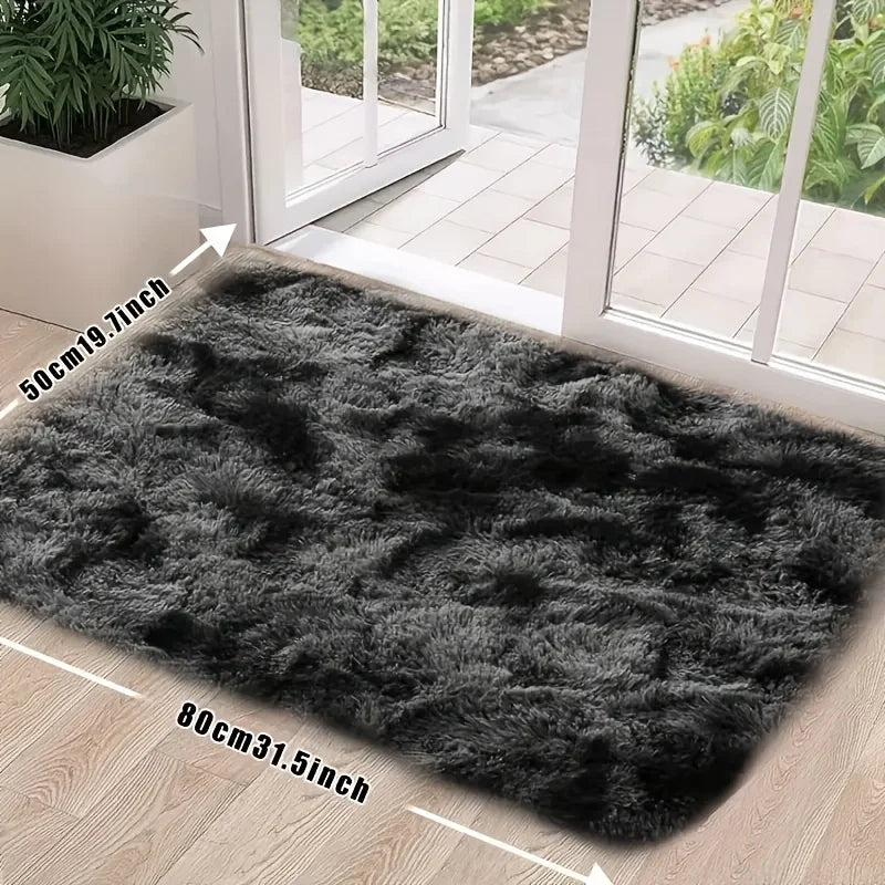 A rectangular dark gray faux fur rug placed on a light wood floor near a glass door.
