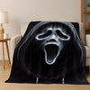 A black flannel throw blanket featuring a stylized, ghostly horror character face with glowing white eyes and an open mouth.