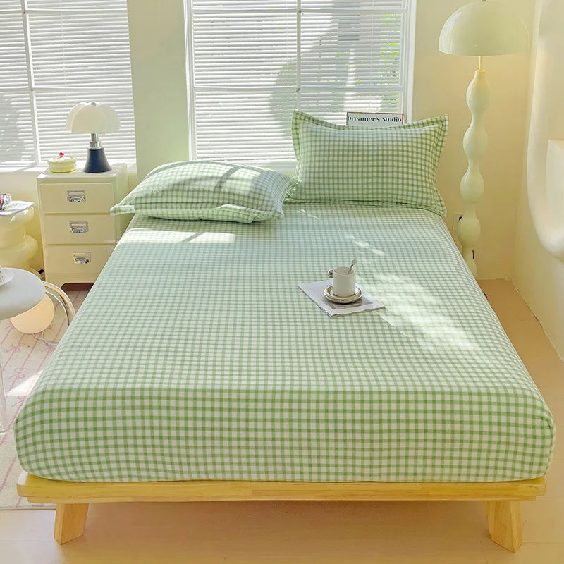 A light green flannel fitted sheet with a white gingham pattern is laid out on a wooden bed frame.