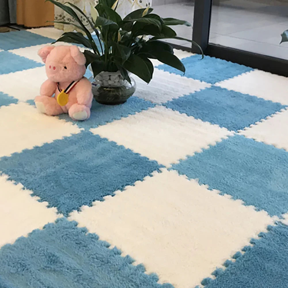A soft pink plush toy sits on a blue and white diamond patterned mat with green foliage in a vase.