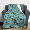 A teal flannel blanket featuring a pattern of brown and white dachshunds on a gray armchair.