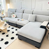 A modern gray sofa with a textured slipcover is shown in a bright living room setting.