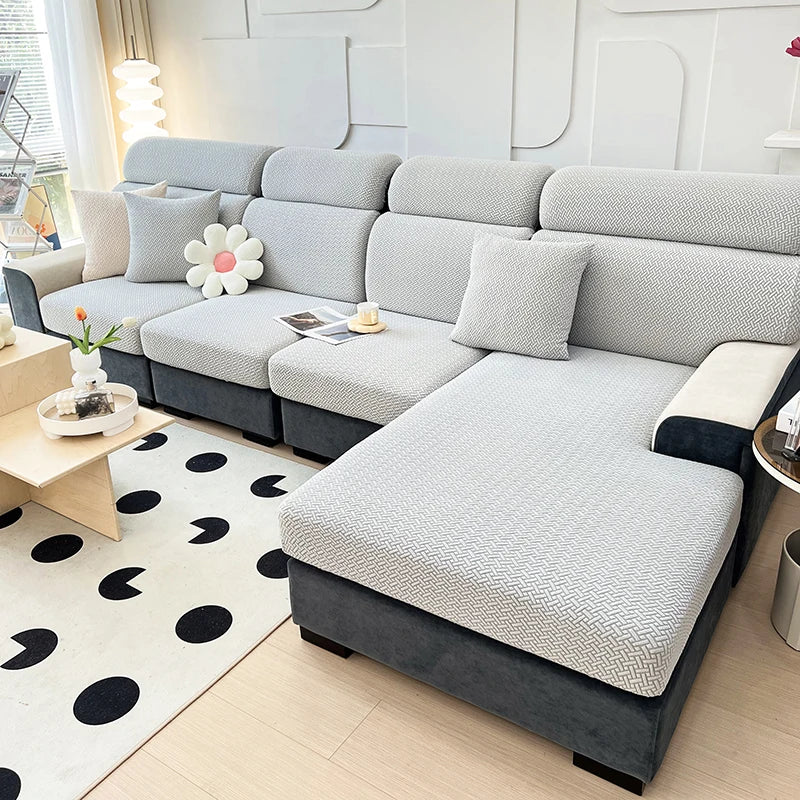 A modern gray sofa with a textured slipcover is shown in a bright living room setting.