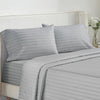 A set of gray and white striped luxury bedding, including pillows and a duvet cover, on a bed.