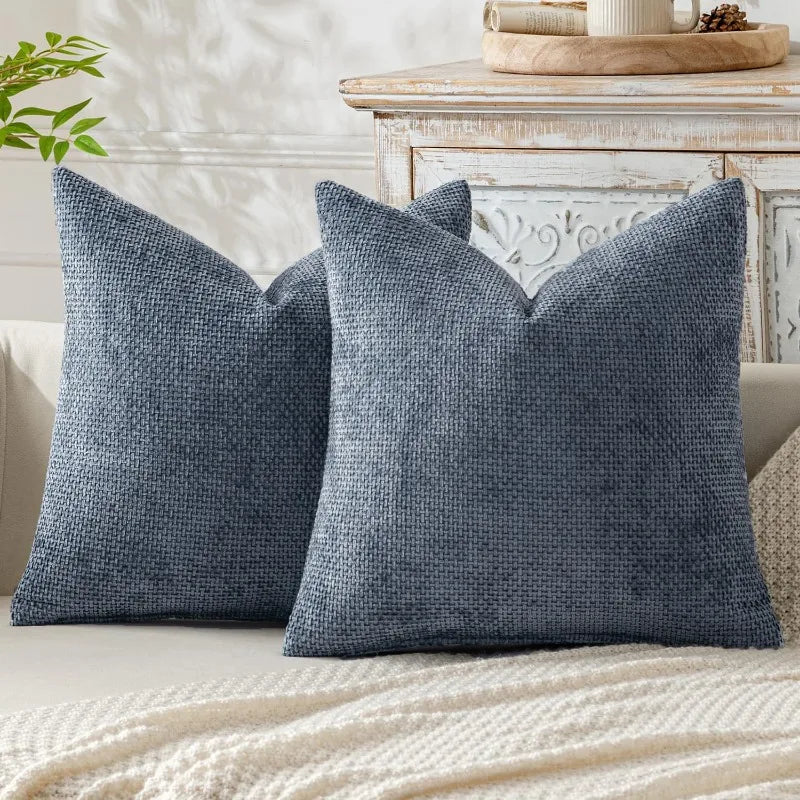 A dark blue textured chenille pillow cover with a minimalist design resting on a light-colored surface.
