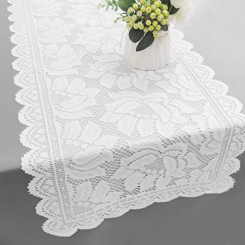 White lace table runner with a delicate floral arrangement on a white vase.