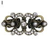 Vintage gold-toned swirl clip brooch featuring clear rhinestones and antique metalwork.