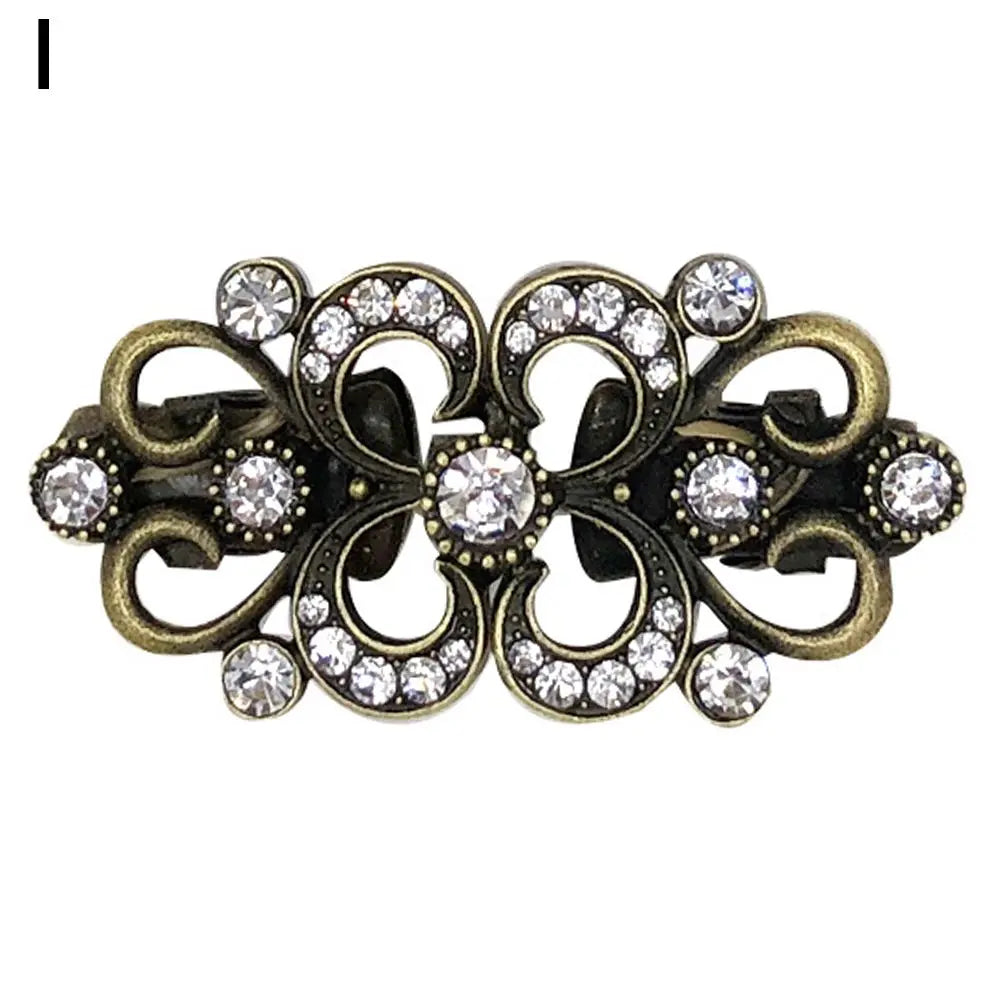 Vintage gold-toned swirl clip brooch featuring clear rhinestones and antique metalwork.