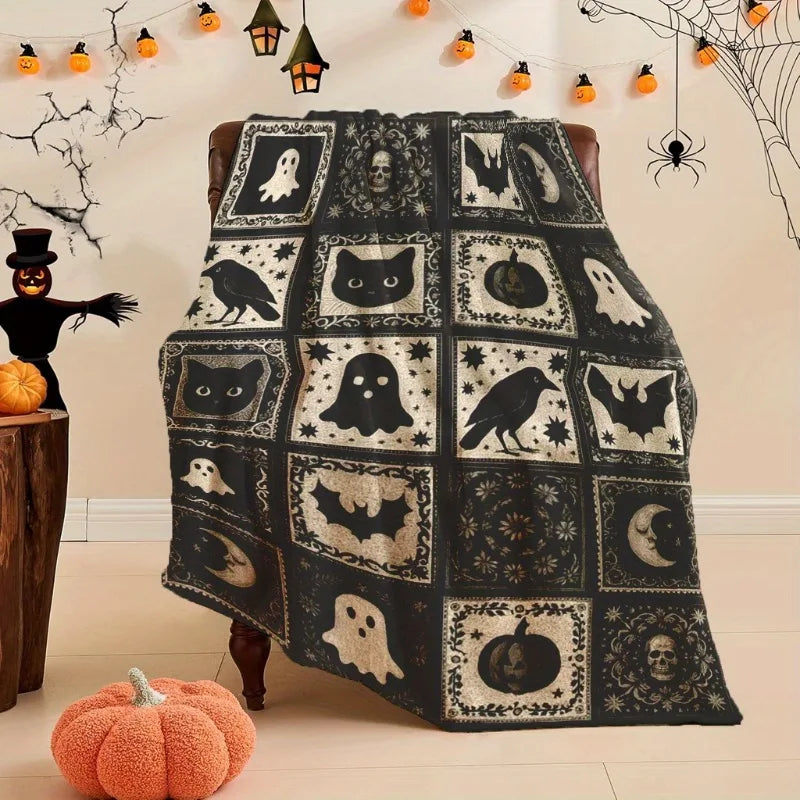 A black and white patchwork throw blanket featuring various spooky Halloween motifs like bats ghosts and pumpkins.