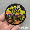 Embroidered patch featuring a stylized tree silhouette against an orange sunset background.