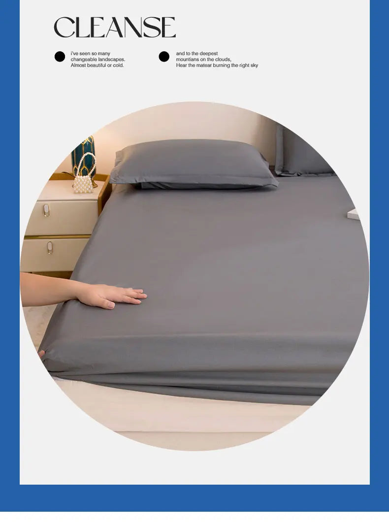 A smooth gray waterproof fitted bed sheet is draped over a bed, with a hand resting on the fabric.