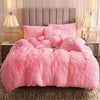 A fluffy pink plush duvet cover set displayed on a bed with neutral bedding and bedside lamps.