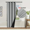 A gray blackout curtain hanging on a rod next to a window.