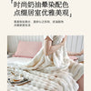 A fluffy white plush rabbit fur throw blanket draped over a person in a bright, soft indoor setting.