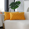 Two yellow quilted velvet decorative pillow covers resting on a white sofa.