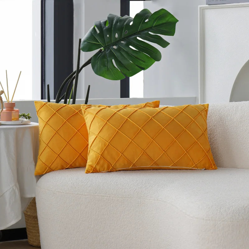 Two yellow quilted velvet decorative pillow covers resting on a white sofa.