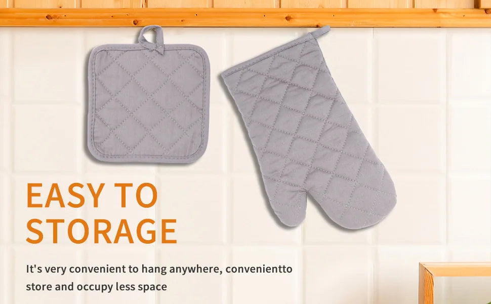 A pair of grey quilted insulated heat resistant cooking gloves hanging on a kitchen backsplash.