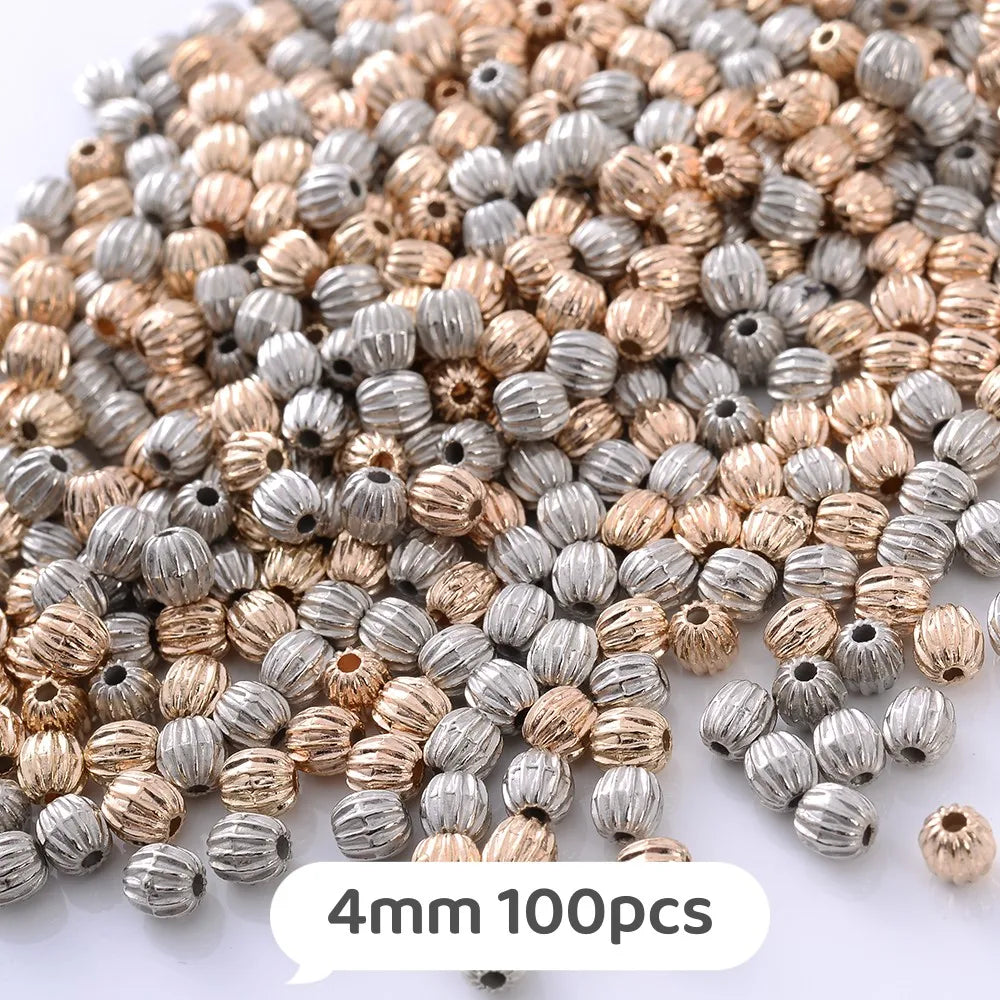 A mix of small, round geometric acrylic beads in silver and gold tones for jewelry making