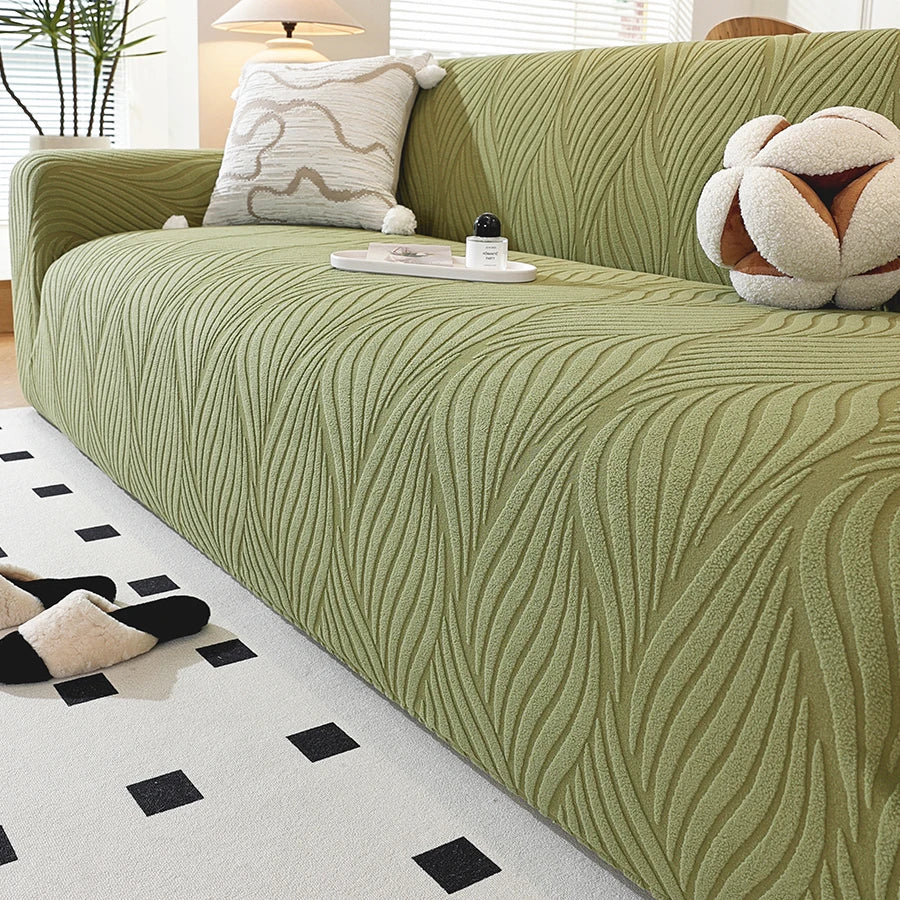 A light olive green stretch sofa cover featuring a vertical wavy pattern and an elastic edge, displayed on a sofa.