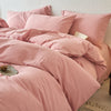 A pink cotton yarn-dyed duvet cover with matching pillows and bedding on a bed.