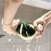 Hands are washing a leaf-shaped fabric hand towel under running water.