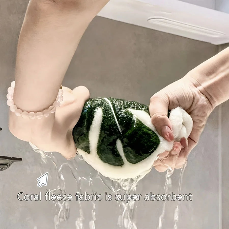 Hands are washing a leaf-shaped fabric hand towel under running water.