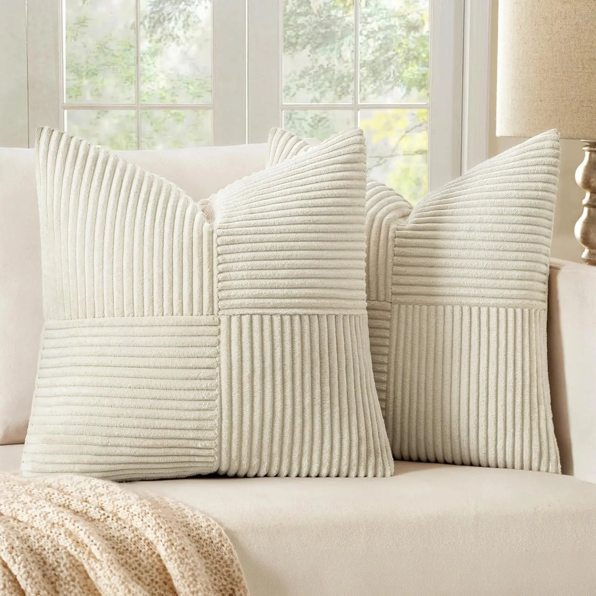 A set of four neutral corduroy throw pillow covers with a vertical ribbed and patchwork design on a light sofa.