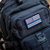 Close-up of a black tactical bag featuring a USA flag patch with hook and loop backing.