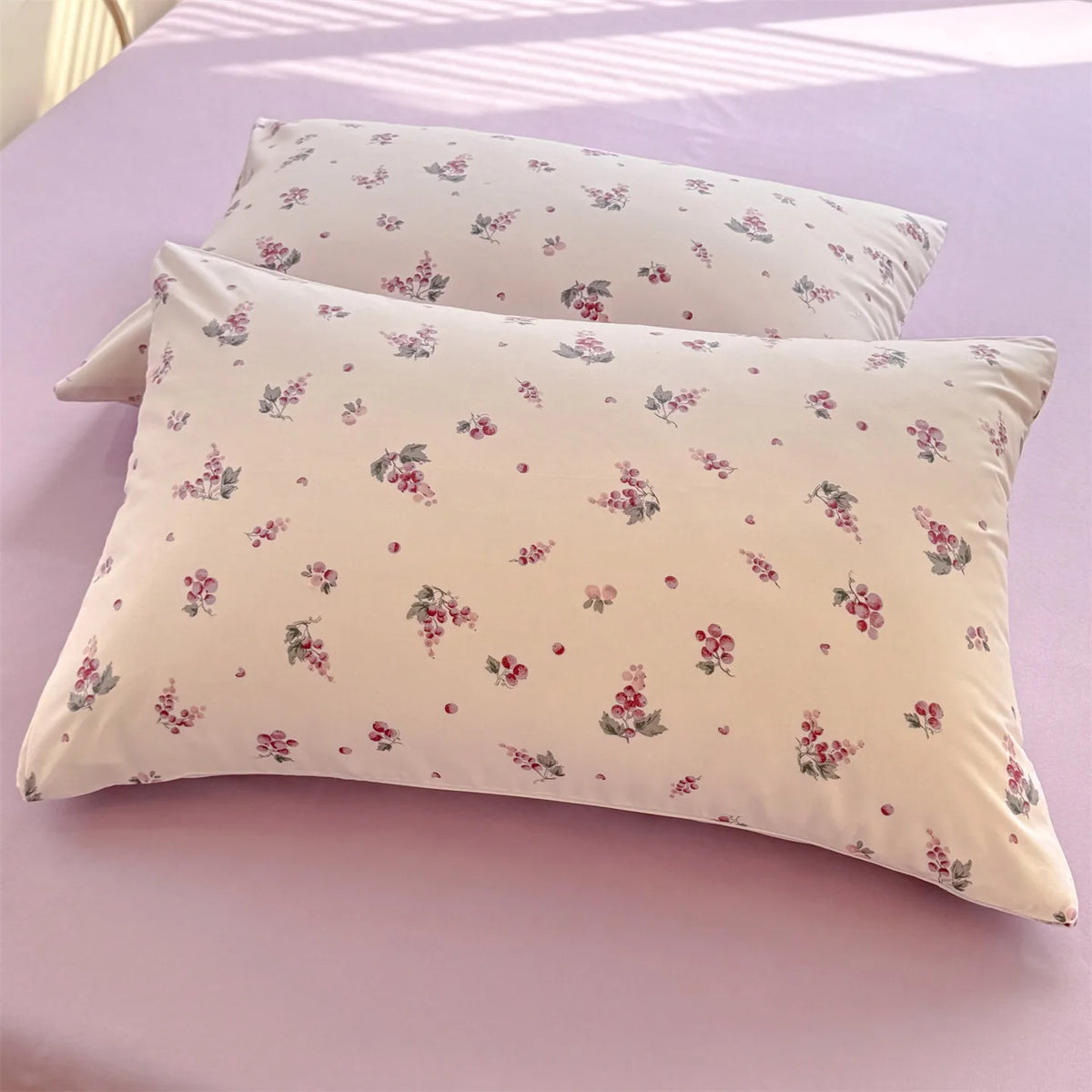 A stack of light pink floral printed pillow covers resting on a purple surface.