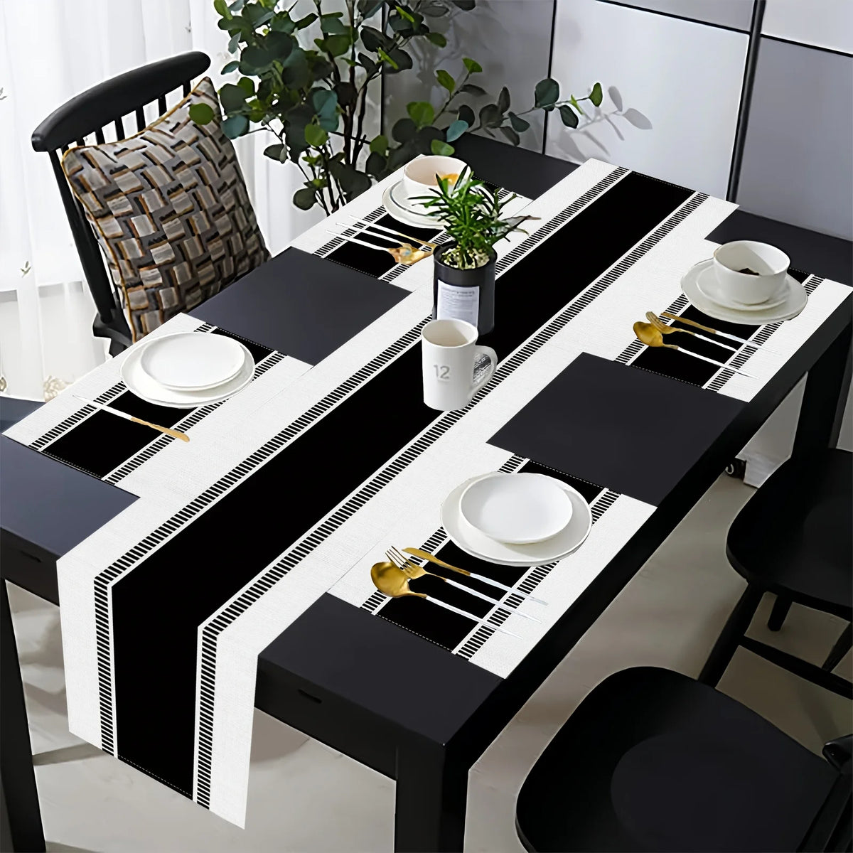 A long dining table set featuring black and white placemats, napkins, and cutlery on a white tablecloth.