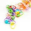 A collection of colorful plastic stitch markers in various shades including green, purple, orange, and pink.