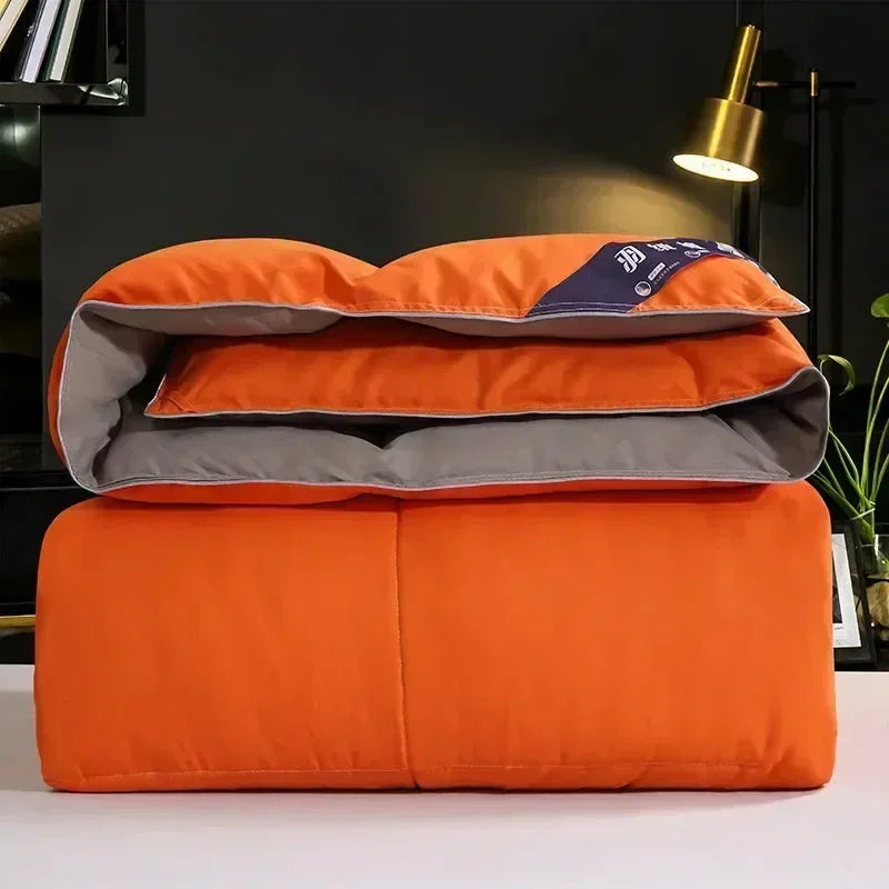 Orange goose down comforter duvet folded on a white surface.