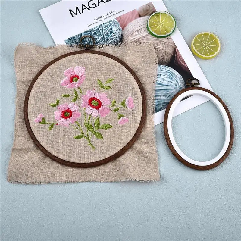 Round wooden embroidery hoops with pink floral designs and natural yarn materials.