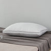 A white luxury goose down and feather bed pillow resting on a gray blanket.
