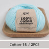 A ball of light blue organic cotton yarn labeled QJH 100% COTON ORGANIQUE resting on a wooden tray.